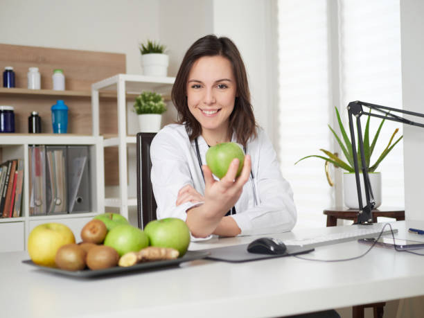 istock Young Female nutritionist holding a green apple 1391914086