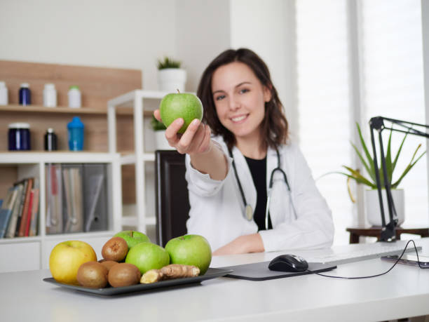 istock Young Female nutritionist holding a green apple 1391914097