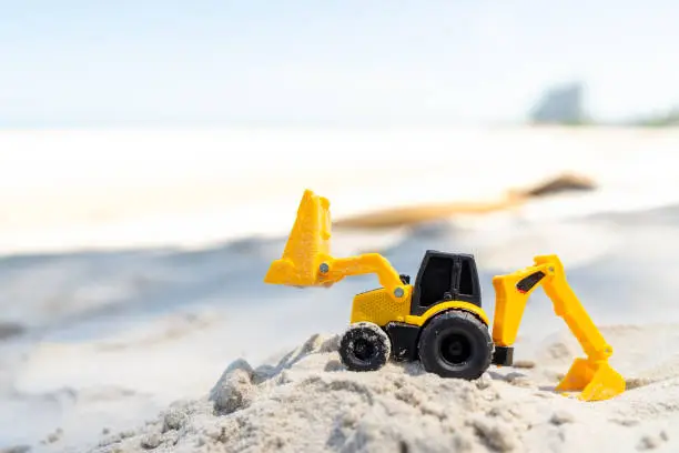 Backhoe toy yellow plastic on beach sand