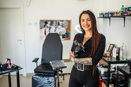 Young beautiful tattoo artist posing in her tattoo studio