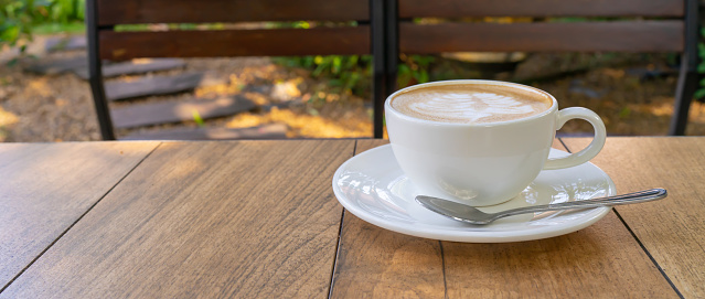 Top view of Latte coffee or cappuccino coffee in white cup with beautiful tree latte art on wooden table.