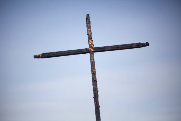 Burnt cross on a blue background. Two daughters covered with coal. Religious symbol. Mystical rite. Sign of Christianity.