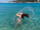 istock Little girl splashes water with her hair. Slow motion. 1391922121