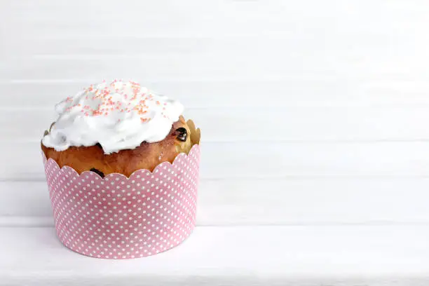 cupcake with raisins and white icing in paper decorative packaging on the table