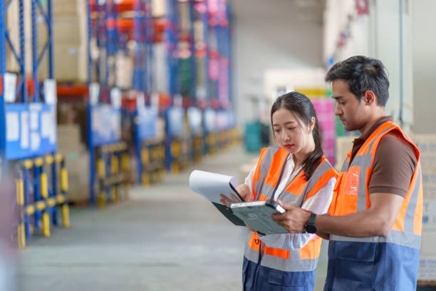 Warehouse workers discussing on shipping schedule. Male and Female warehouse workers discussing shipping schedule next to the forklift. Warehouse and Logistic business concept. manufacturing occupation photos stock pictures, royalty-free photos & images