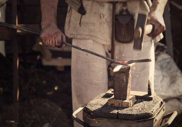istock Blacksmith forges part on anvil in antique clothes 1391926359