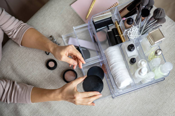 Closeup female hands putting luxury cosmetic into acrylic box with drawer storage organization stock photo