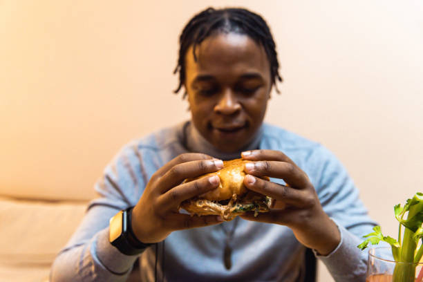 istock Young African American man enjoying eating burger and drinking cocktail 1391931003