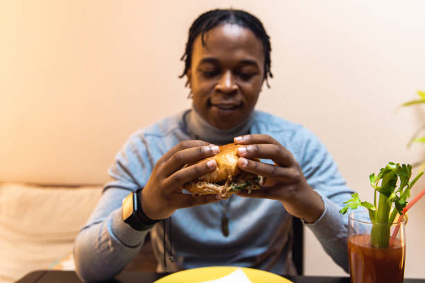 istock Young African American man enjoying eating burger and drinking cocktail 1391931037