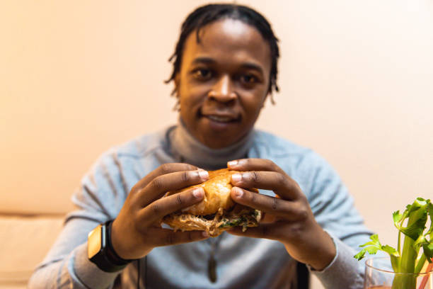 istock Young African American man enjoying eating burger and drinking cocktail 1391931065