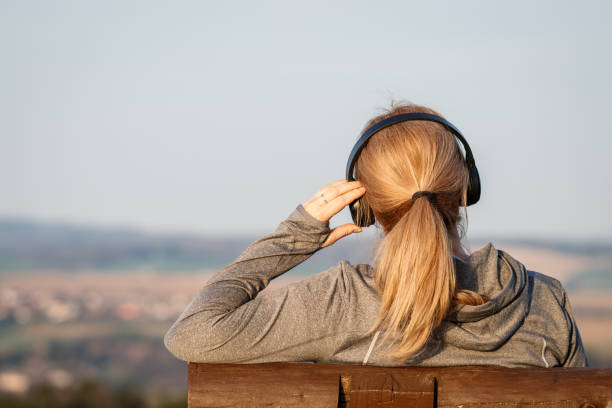 Woman with headphones sitting on bench and listening music stock photo