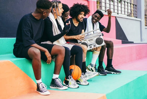 grupo de jovens africanos ouvindo música de som boombox vintage ao ar livre após jogo de basquete - foco no homem com cabelo afro encaracolado - estilo musical - fotografias e filmes do acervo