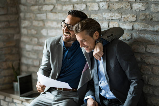 Two happy businessmen laughing together in office after seeing great results. stock photo