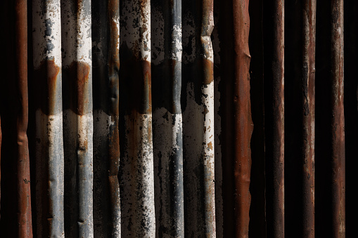 Corrugated iron fence detail with peeling paint.