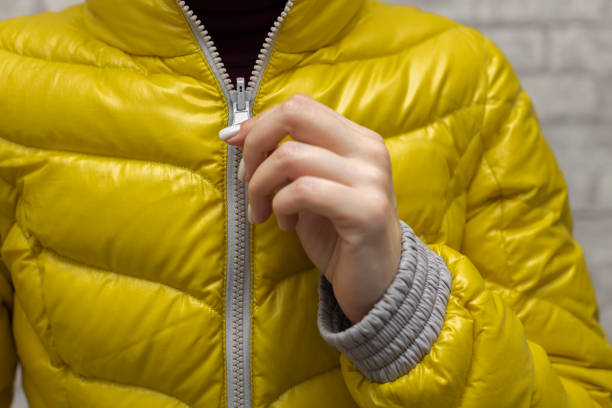 eine frau reißt ihre jacke um den hals - reißverschluß stock-fotos und bilder