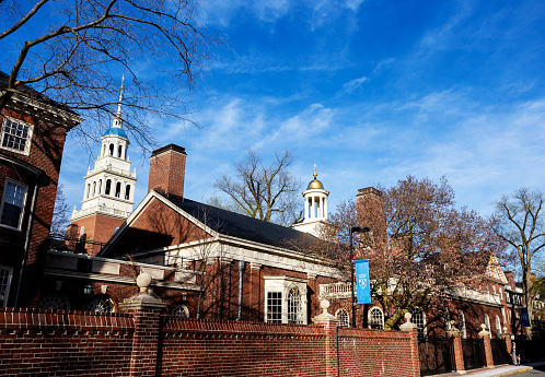 Cambridge, Massachusetts, USA - April 11, 2022: Lowell House along Mill Street on the Harvard University campus. One student walking.