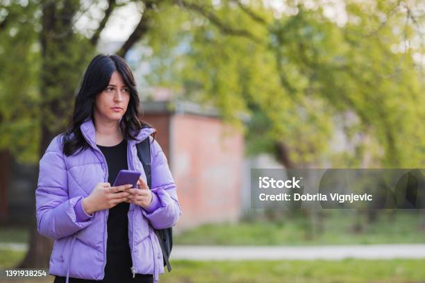 Girl Holding Smart Phone When Standing In The Park Stock Photo - Download Image Now - Acne, Adulation, Adult