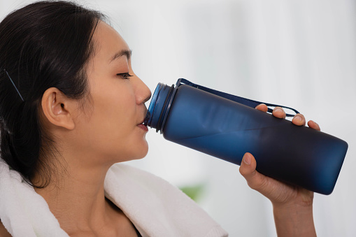 Asian woman exercising, drinking water and resting after exercise.lifestyle and healthy concept.
