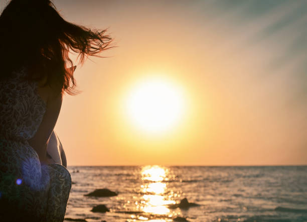 istock woman on sea shore at sunset 1391942049