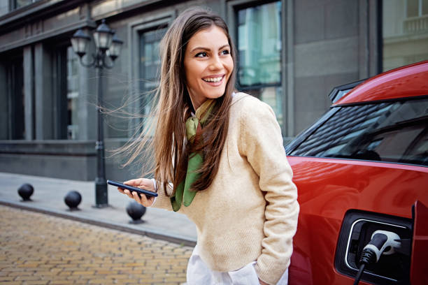 Portrait of woman charging her electric car stock photo