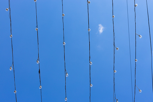 Light bulbs rows on wires against clear blue sky background