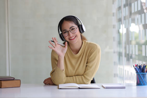 a jovem tem uma chamada de vídeo com seu colega. mulher blogueira professora senta-se em home office fazendo, entrevista de emprego on-line durante chamada de conferência de vídeo chat, registro vlog ensinando em webinar no aplicativo, visão webcam. ol - looking at camera smiling desk isolated - fotografias e filmes do acervo