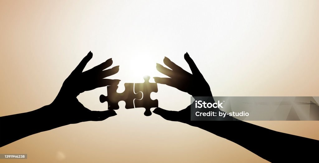 Two hands put two pieces of the puzzle together Color Image Stock Photo
