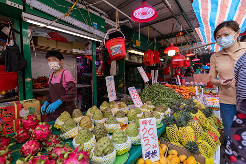 Hong Kong - April 12, 2022 : Shoppers at a fruit store in Mong Kok, Kowloon, Hong Kong.