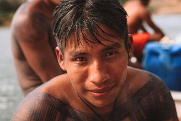 Indigenous young man with face paint river swimming Indigenous man from an Amazon tribe in Brazil with tribal art painted on his body, swimming in the Xingu River. Jogos Indígenas 2010. indigenous peoples day stock pictures, royalty-free photos & images