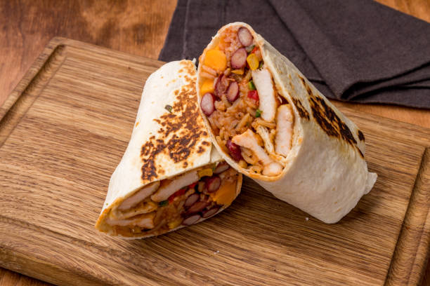 istock Mexican chicken burrito on wooden board side view 1391960247