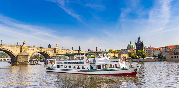 Prague, Czechia - September 17, 2022:  Tourist passenger ferry boat floats by the Manes bridge over the Vltava River in Czech Republic Czechia Europe