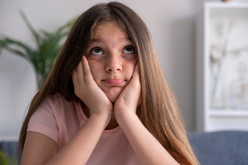 beautiful teenage girl sitting at home working desk  with her head in hands.