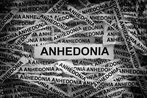 Strips of newspaper with the words Anhedonia. Black and white. Close up.