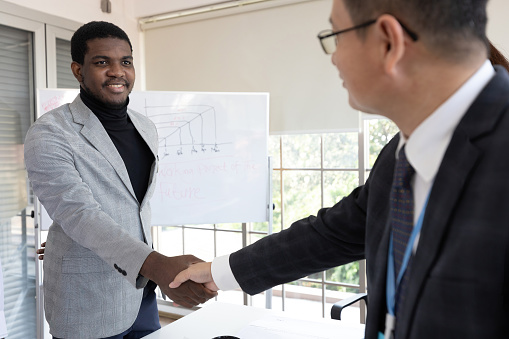 Successful business partners closing deal. Closeup of multiethnic businesspeople shaking hands Handshake concept