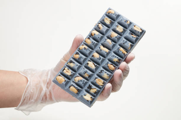 Hand holding blue chocolate bar with whole peanut filling stock photo