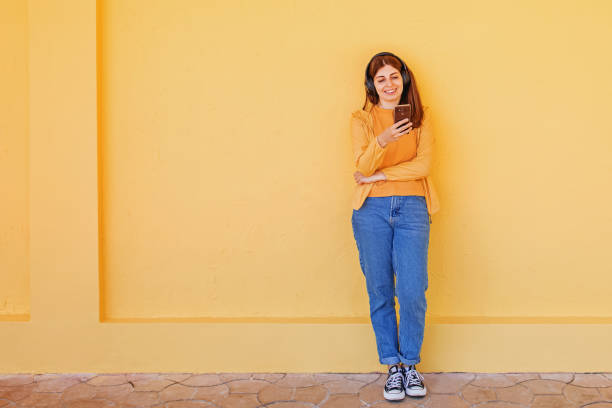 istock A young woman using her smartphone near yellow wall 1391965374