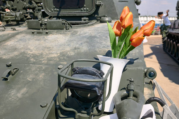 tulipanes rojos en un jarrón de pie en un vehículo blindado de combate de infantería - war globe symbols of peace weapon fotografías e imágenes de stock