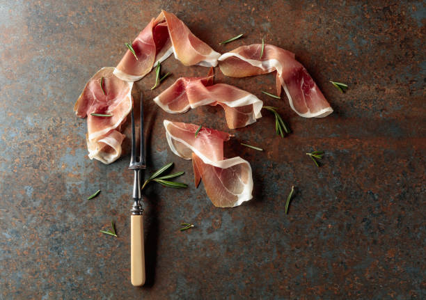 Prosciutto with rosemary on vintage background. stock photo
