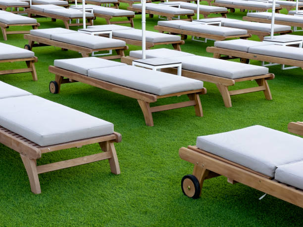 Empty wooden sun beds on a green carpet at the hotel stock photo