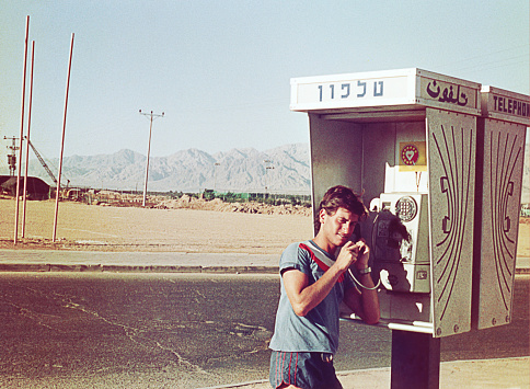 Young man talking on a public phone booth