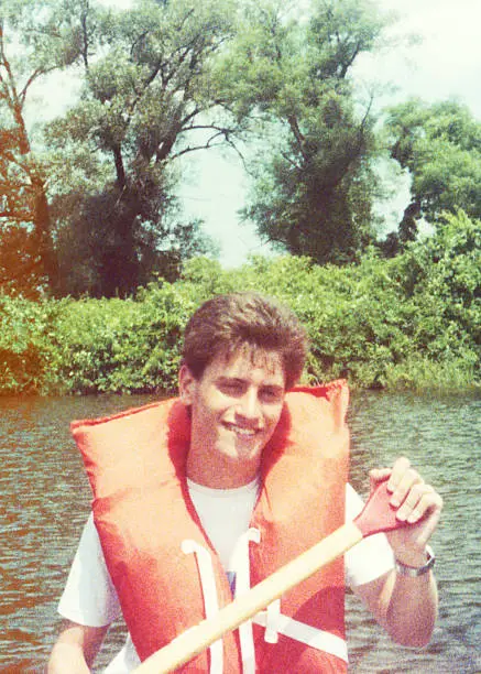 Analog image of a teenage boy rowing and looking at the camera. Very grainy image form the eighties.