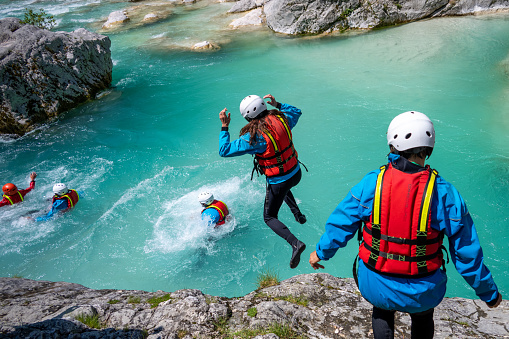 Adventurous teambuilding in mountains. Adrenaline jumping into cold water in gorge. Amazing turquoise clear water in Soca river, Slovenia.