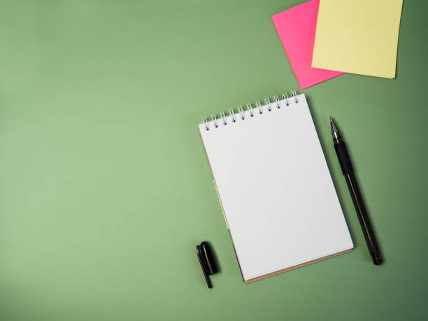 istock blank notepad, pen and stickers on a green background with space for text 1391968833