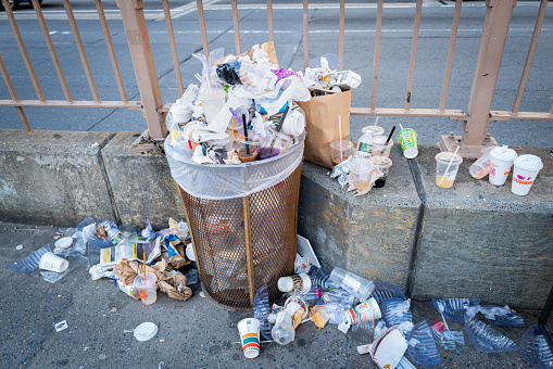 Manhattan, New York, United States - April 14, 2022: Over filled trash can at the base of the Brooklyn Bridge on the Manhattan side of bridge.