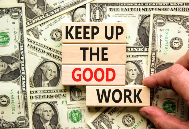 Keep up the good work symbol. Concept words Keep up the good work on wooden blocks. Businessman hand. Beautiful background from dollar bills. Keep up the good work business concept. Copy space.