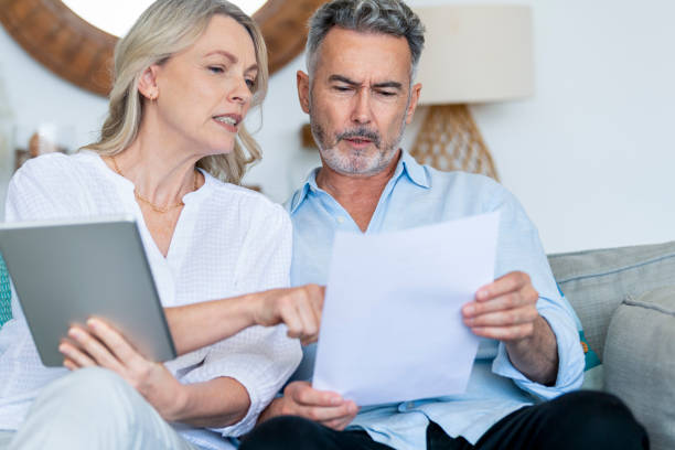 istock Worried mature couple using digital tablet and doing paperwork on the sofa. 1391970127