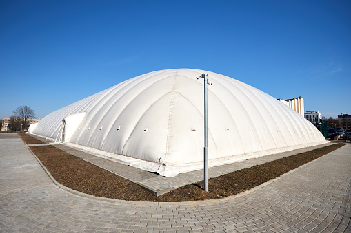 Grodno - April 2022: Inflatable air dome stadium. Inflated Tennis air dome or Tennis bubble arena. Modern urban architecture example, as pneumatic stadium dome.
