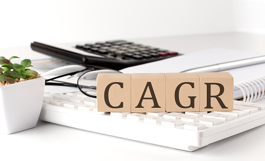 CAGR written on wooden cube on keyboard with office tools