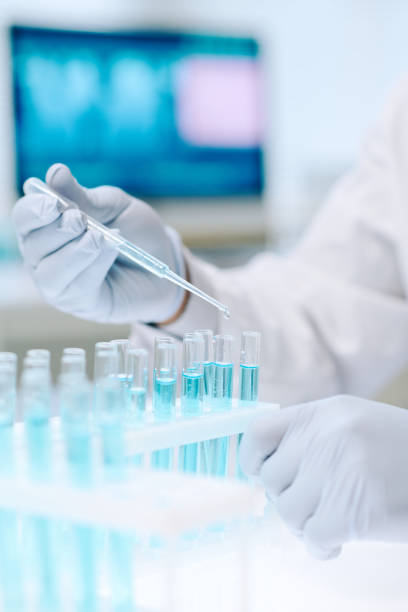 istock Chemist mixing two liquid substances while dropping one of them into flask 1391972409