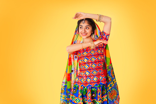 Beautiful indian race woman wearing ethnic indian dress isolated on yellow background with copy space.
